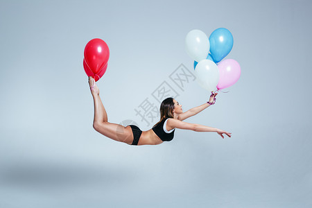 轻的体育女子悬浮气球上轻盈的图片