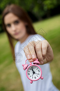 轻的成妇女女孩外着粉红色的闹钟,及时跑出照片背景图片
