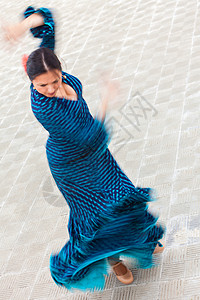 动作模糊慢快门速度拍摄的女传统西牙弗拉门戈舞蹈跳舞的蓝色波尔卡圆点连衣裙背景图片