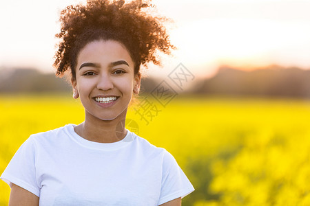 户外肖像美丽的快乐混合种族非裔美国女孩十几岁的女轻女子微笑与完美的牙齿片花田背景图片