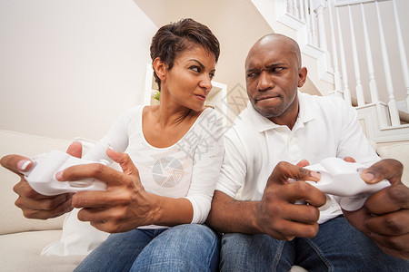 非裔美国人夫妇,男人女人,玩电子游戏机游戏,激烈的竞争中互相看着,别之战图片