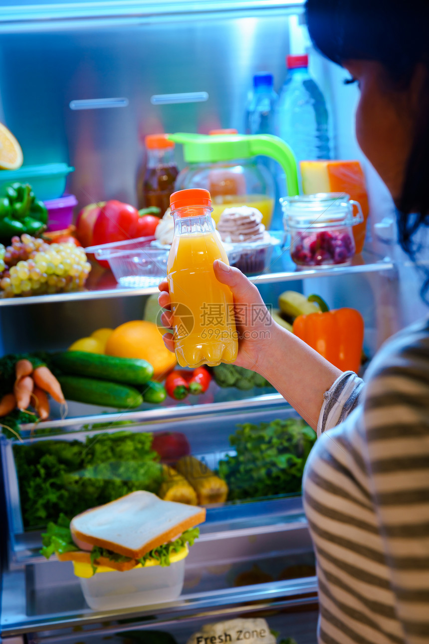 女人打开的冰箱里橙汁图片