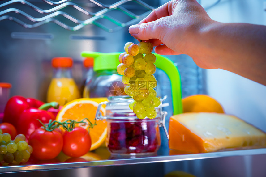 女人敞开的冰箱里出串葡萄健康的食物图片
