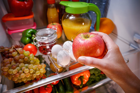 女人打开的冰箱里苹果健康的食物图片