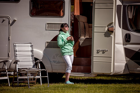 女人站露营车旁边着杯咖啡房车度假家庭度假旅行,汽车之家度假旅行图片