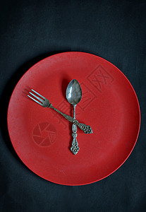 生锈的背景上红色盘子勺子叉子的时钟图片
