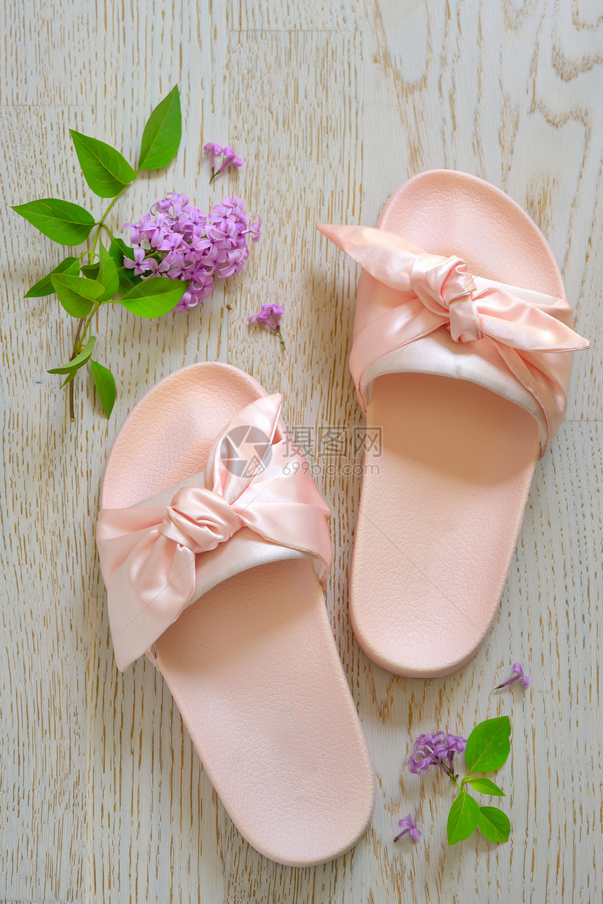 木制背景上的玫瑰粉红色女子拖鞋图片