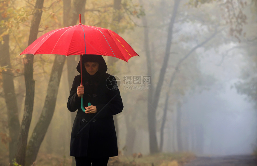 沮丧的女人带着红色的伞雾蒙蒙的森林图片