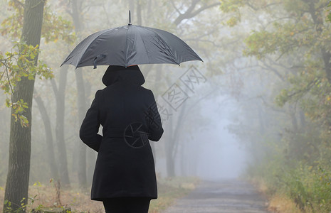 沮丧的女人带着红色的伞雾蒙蒙的森林高清图片