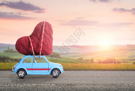 蓝色复古玩具汽车为情人节传递心,抗模糊的乡村托斯卡纳日落景观图片