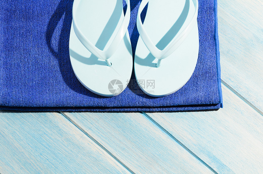 桌子上的海滩配件海滩配件蓝色木制桌子上毛巾拖鞋的时尚太阳镜图片