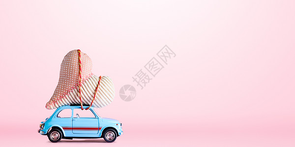 蓝色复古玩具汽车为情人节提供粉红色背景的工艺心图片