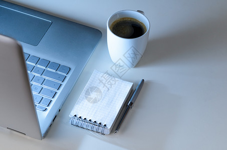 现代笔记本电脑夜间工作场所,咖啡杯笔记本与笔,看图片