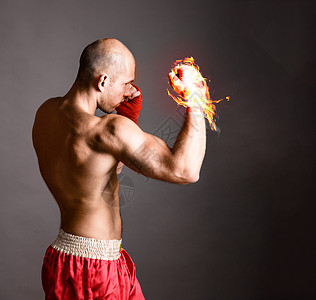 火焰拳打拳击手武术战士灰色背景上用火热的手击球背景