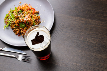 爱吃啤酒的晚餐大拇指黑色桌子上的啤酒璃泡沫上的轮廓与食物,看图片