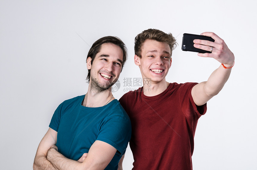 快乐的朋友正自拍两个快乐的朋友手机摄像头上自拍图片