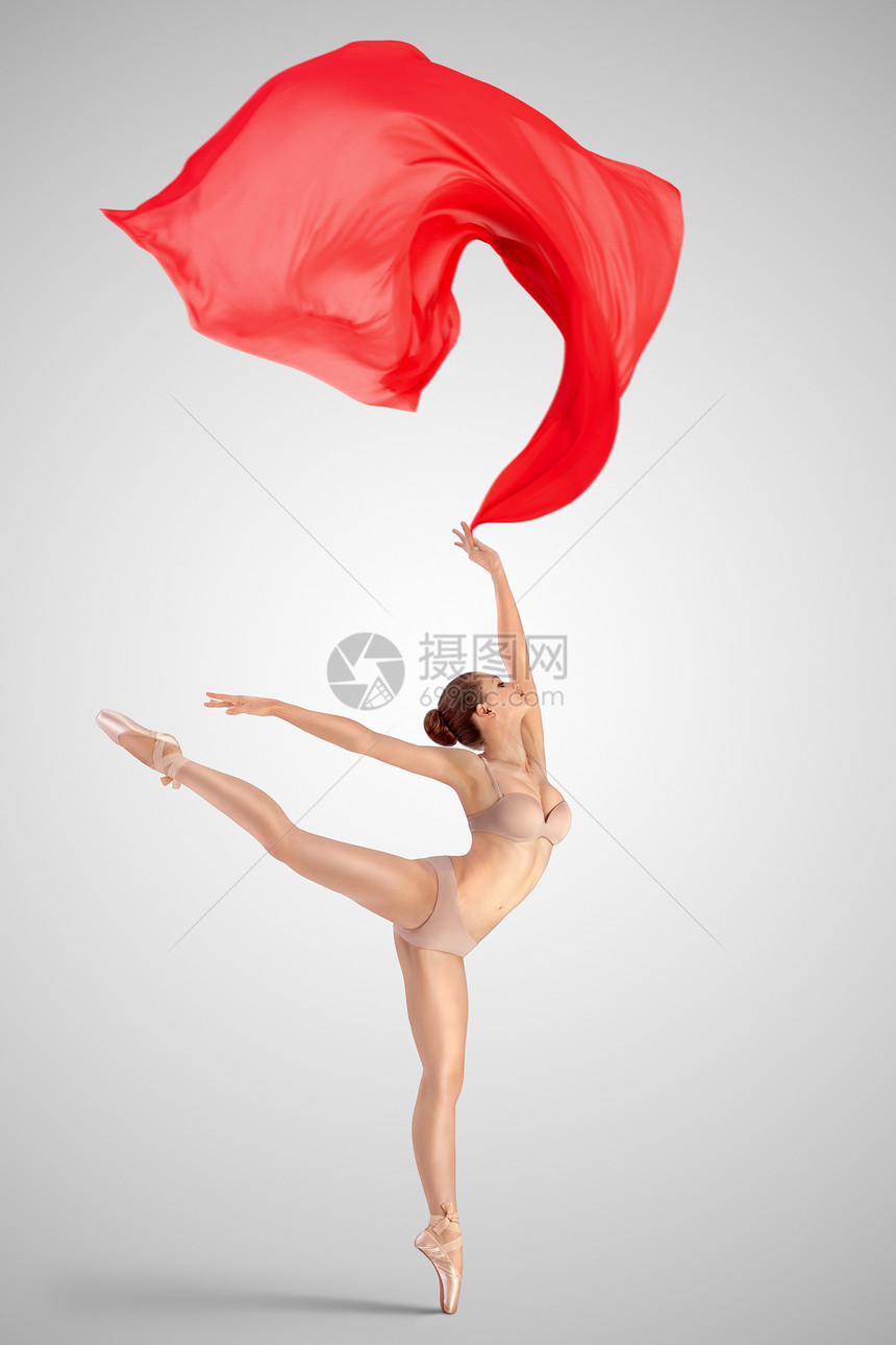 位优雅的女古典芭蕾舞穿着米色内衣,站条腿上,站阿拉伯风格的位置,中灯光工作室背景上扔红色的布料图片