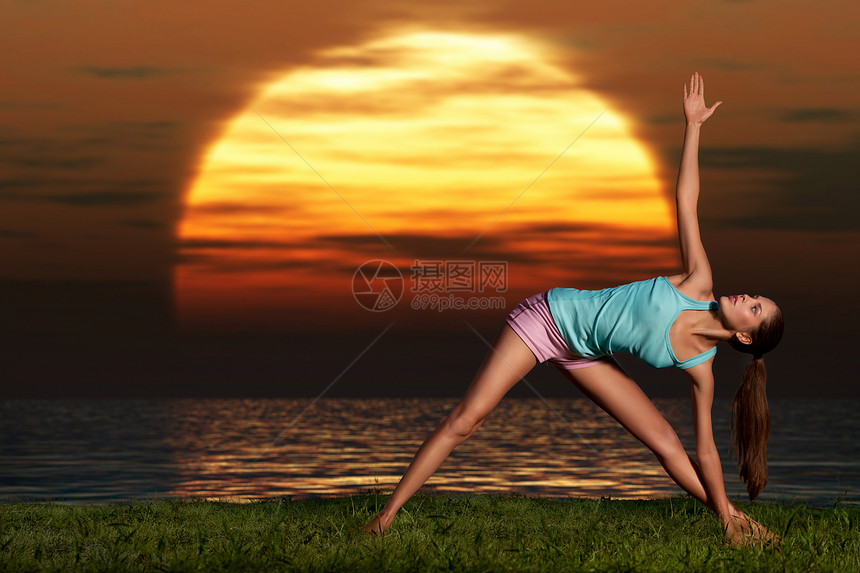 个活泼的美女黎明时海滩上训练瑜伽图片