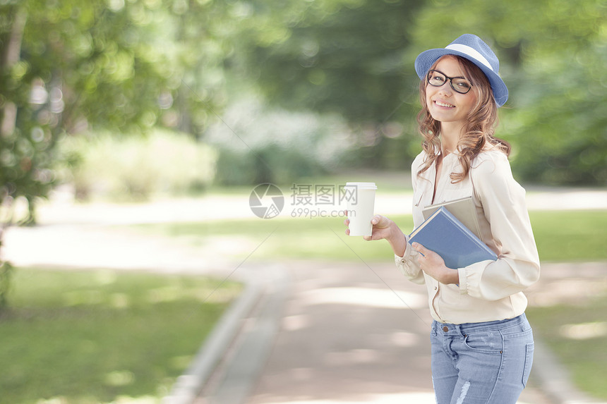 快乐的轻学生喝着咖啡,走夏天的公园里,着书读书学图片
