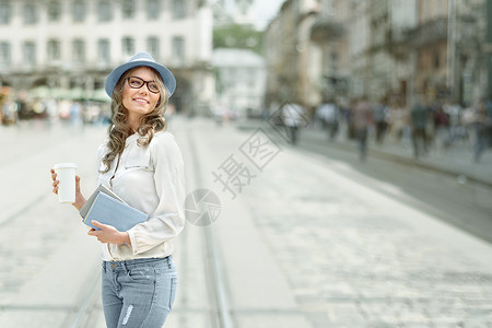 快乐的轻学生,喝着咖啡,着书城市背景下阅读学图片