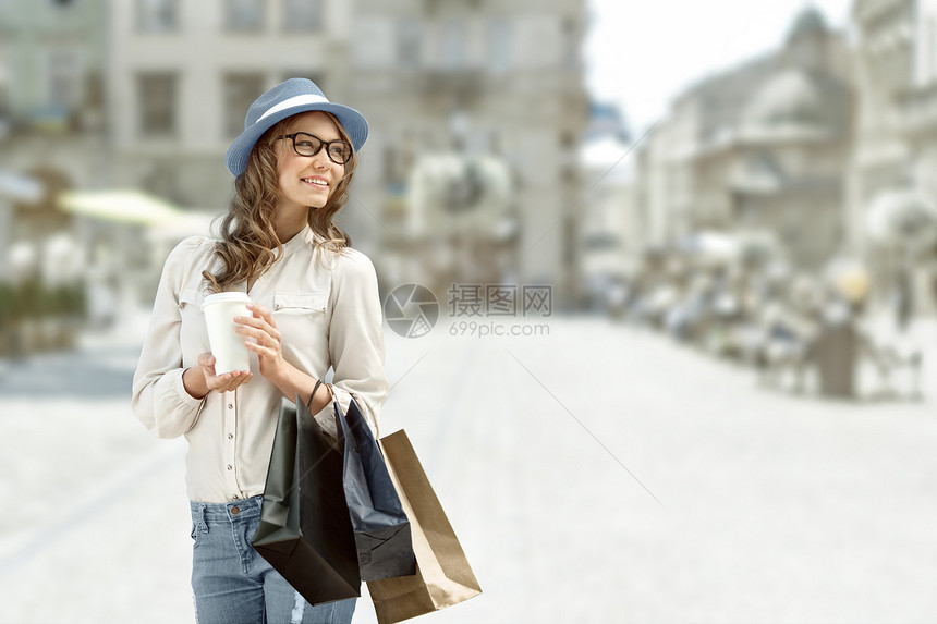 快乐的女人购物后手里拿着咖啡微笑着图片