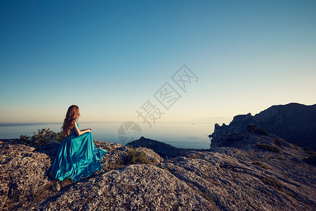 穿着蓝色连衣裙的轻美女望着山海蓝天背景上的自然女孩时尚照片图片
