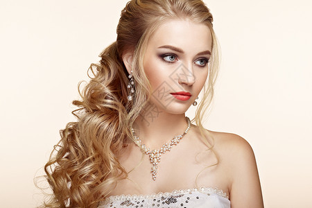 头又长又亮的卷发的金发女孩漂亮的模特,留着卷曲的发型护理美容美发产品完美的化妆珠宝背景图片