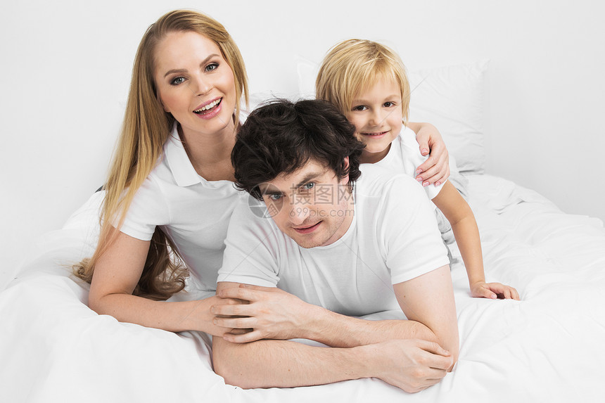 床上微笑的家人微笑的家庭孩子床上醒来图片