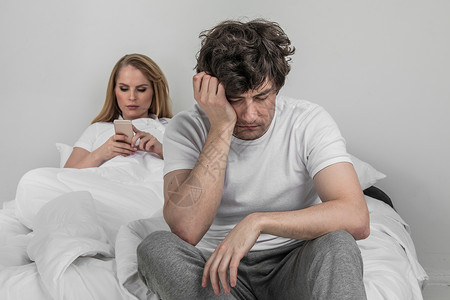 家庭冲突的家庭冲突的,沉迷于手机女人安的男人床上背景图片