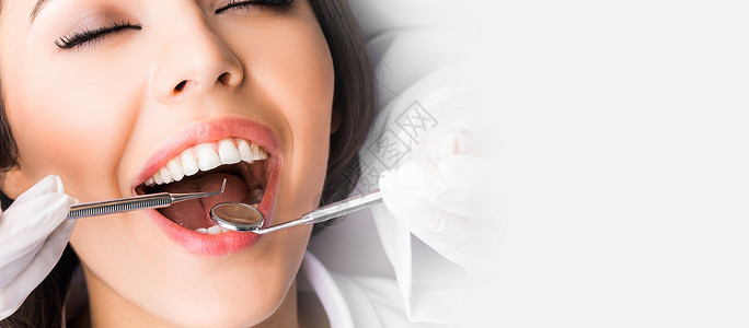 检查病人的牙齿牙医检查病人的牙齿,近距离观看白色拷贝背景图片