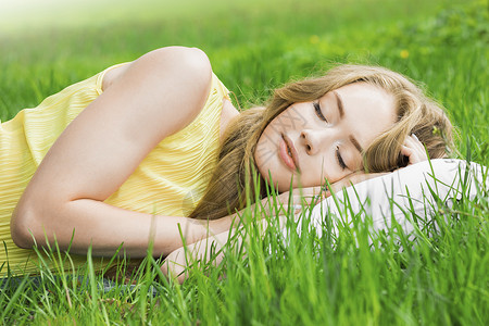 女人睡草地上轻的女人睡清新的春草里的白色枕头上背景图片