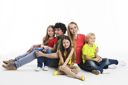 工作室的家庭肖像幸福家庭的肖像与三个孩子坐地板上的工作室白色背景图片