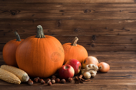 木桌上的秋收秋收生活与南瓜,苹果,榛子,玉米,生姜,洋葱肉桂木制背景图片