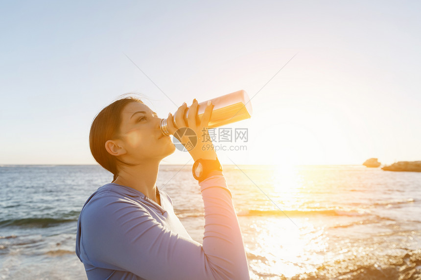 女人海滩上喝水轻女子海滩上锻炼后喝水图片