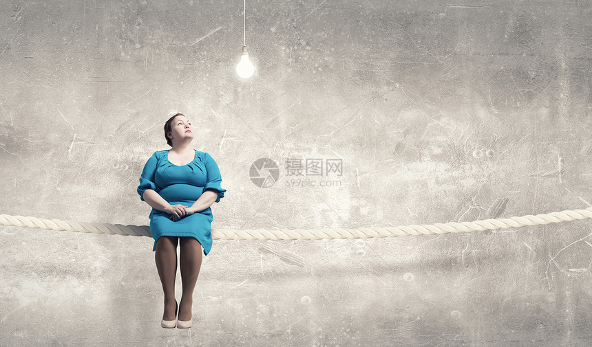 超重问题中胖女人穿着蓝色连衣裙坐绳子上图片