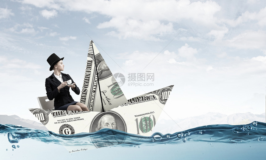 美元纸船女商人漂浮水上的美元钞票上图片