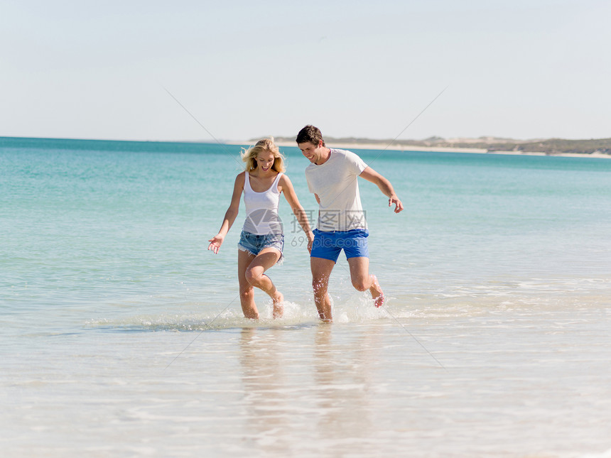 浪漫的轻夫妇海滩上浪漫的轻夫妇海滩上沿着海岸散步图片