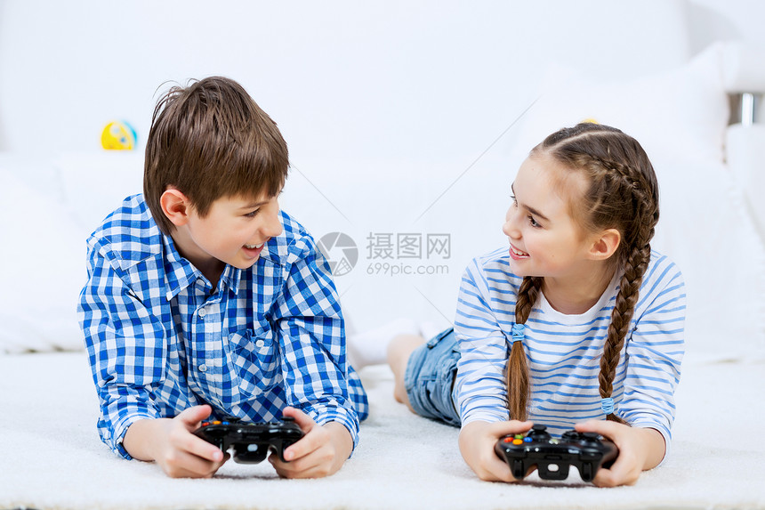 孩子们玩游戏控制台可爱的孩子躺地上,操纵杆上玩游戏图片