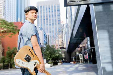 城市里带吉他的轻音乐家城市中轻音乐家与吉他的肖像背景图片