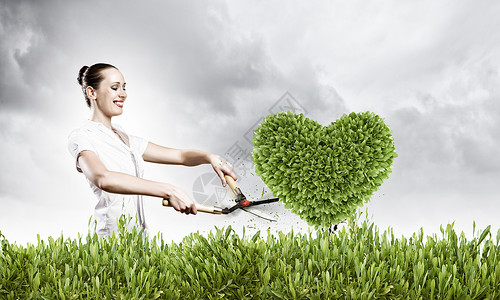 绿色植物轻迷人的女商人剪草坪的心脏形状背景图片