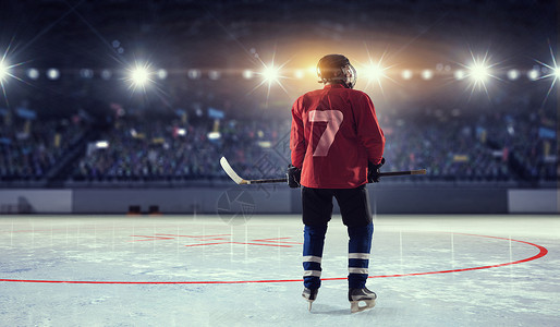 冰球运动员冰上穿着红色制服的曲棍球运动员聚光灯下的冰场上背景图片