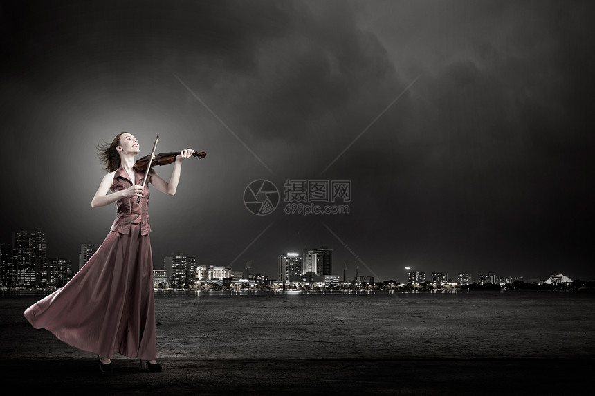 女人拉小提琴轻的女小提琴手,穿着棕色的长裙图片