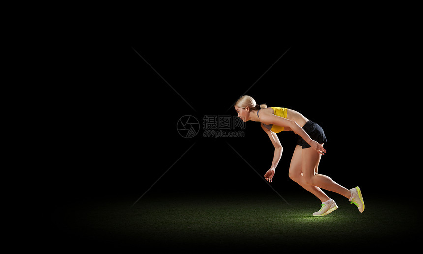 全速前进轻的女运动员黑暗的背景下跑得很快图片