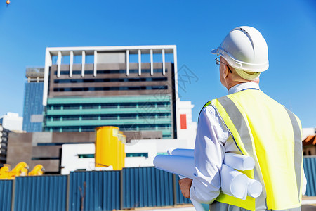 建筑工地的工程师建设者工程师建筑工人施工场景穿着带蓝图的安全背心图片