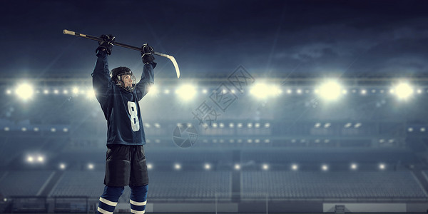 冰球运动员冰上穿着蓝色制服的曲棍球运动员聚光灯下的冰场上图片