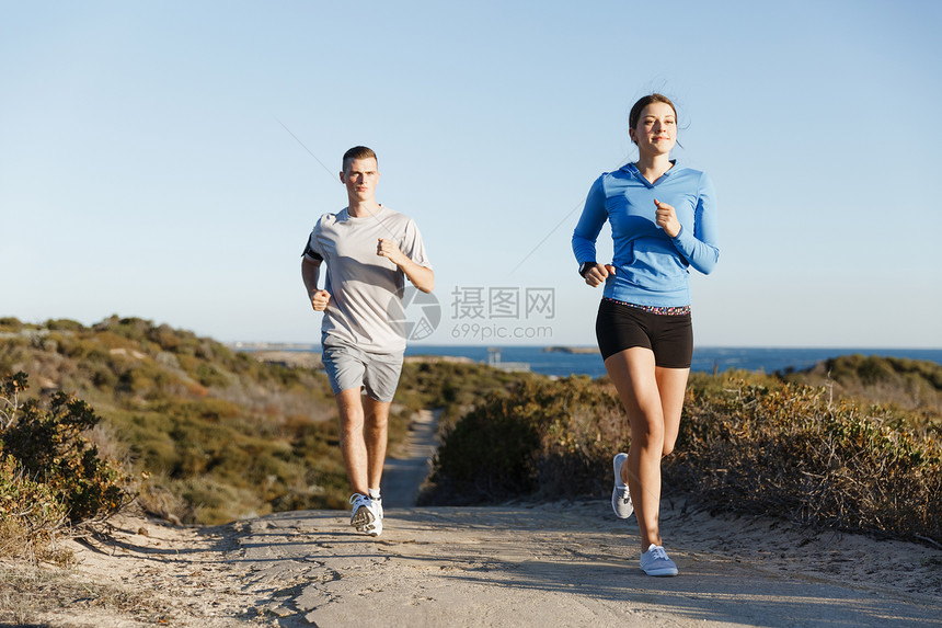 运动跑步者海滩上慢跑,她的搭档锻炼适合女健身模式慢跑沿海洋与她的伴侣图片