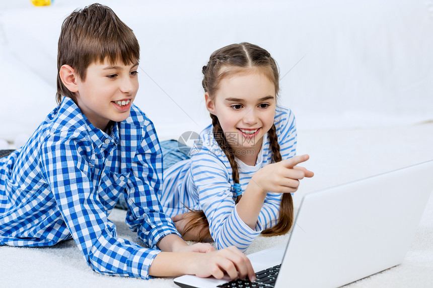 可爱的孩子用设备男孩女孩躺地板上用笔记本电脑图片