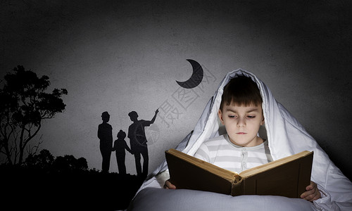 睡觉前读书小可爱的男孩毯子下的床上看书图片