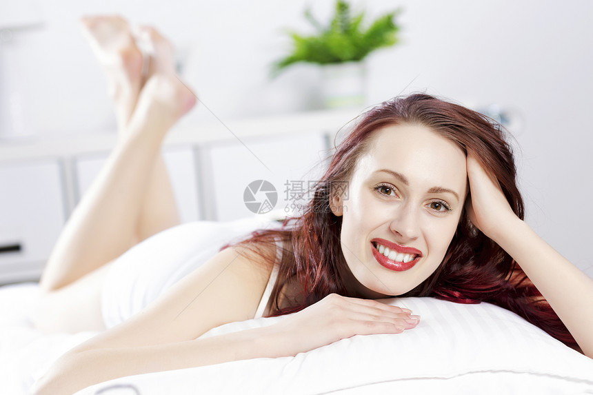 轻快乐的女人躺床上微笑早上好图片
