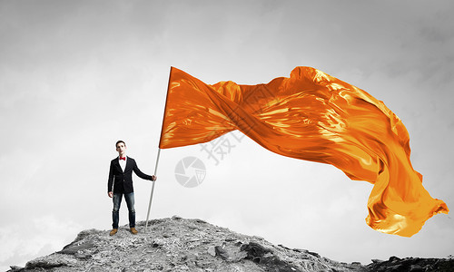 橙色挥舞的人学生家伙穿着休闲,手里着旗子图片